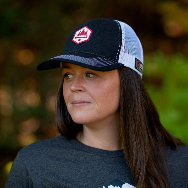 Woman wearing a black with white mesh backed adjustable ball cap with obsc logo
