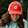 Woman wearing a red with white mesh backed hat, obsc logo, adjustable fit